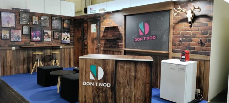DON'T NOD B2B booth with a timber reception desk and lodge-inspired interior
