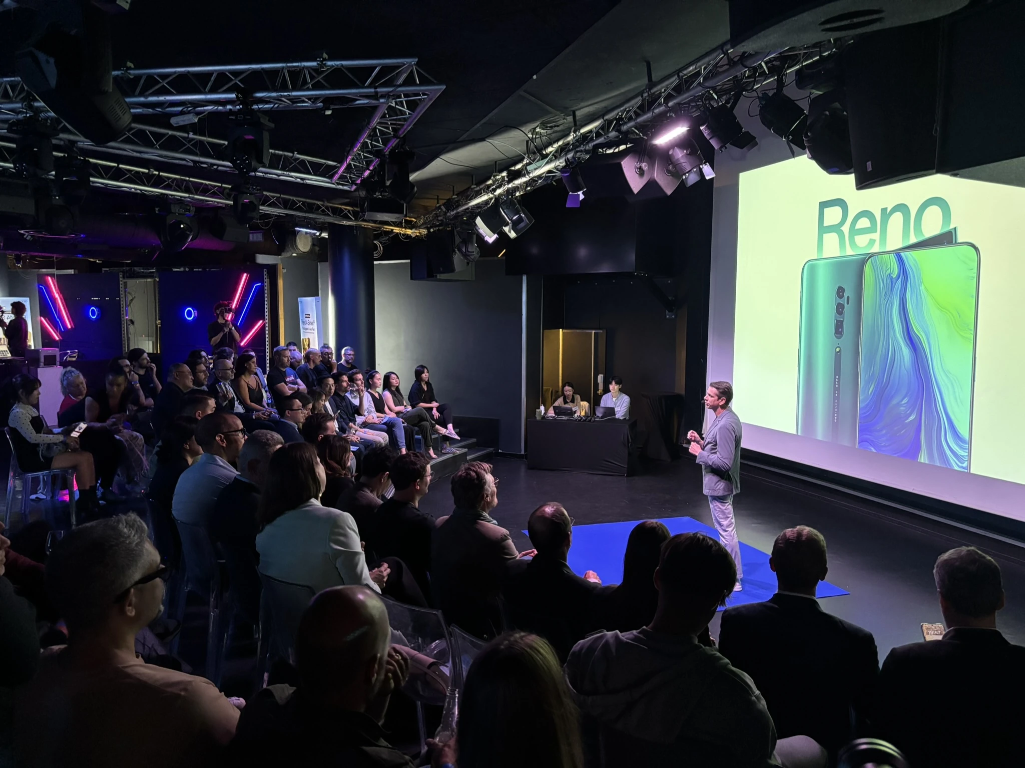 OPPO Reno presentation with a speaker on stage and an audience of event guests