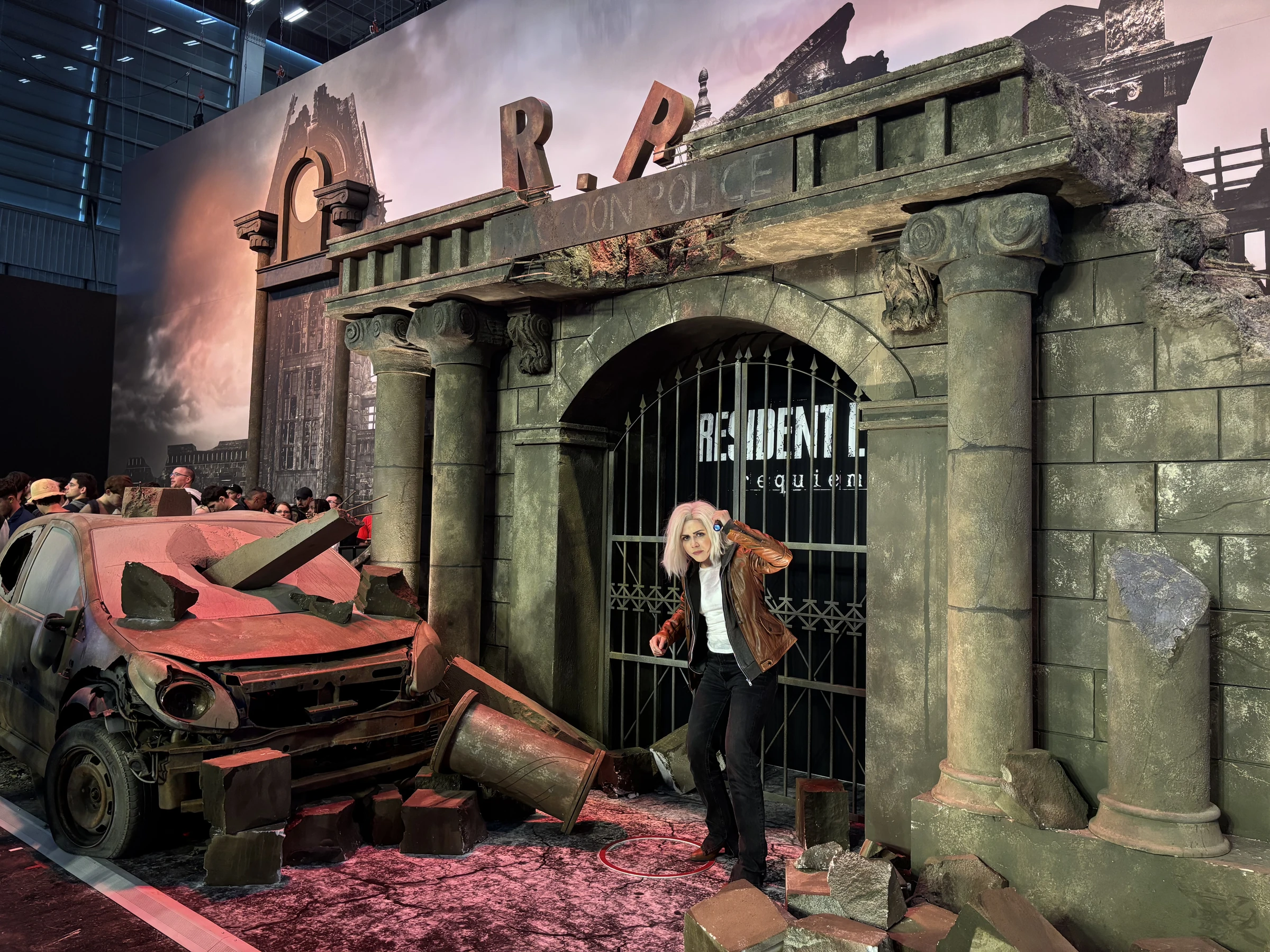 Resident Evil Requiem booth with an immersive stone entrance, a damaged car and a cosplayer